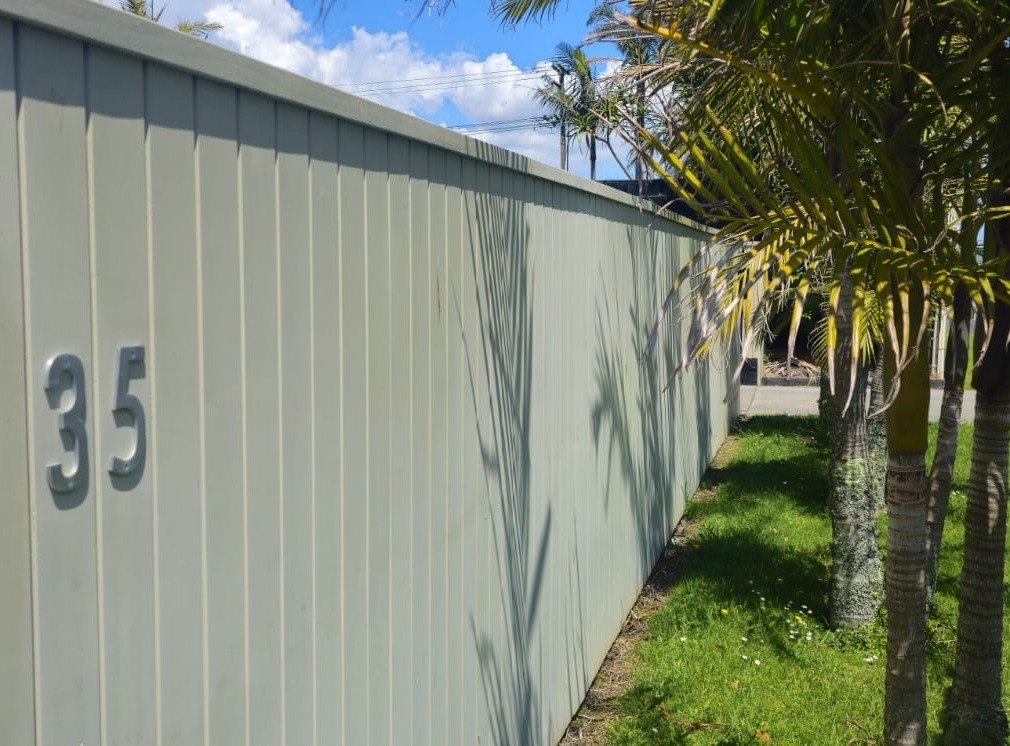 Light‑coloured timber fence with horizontal slats, situated in a landscaped residential yard